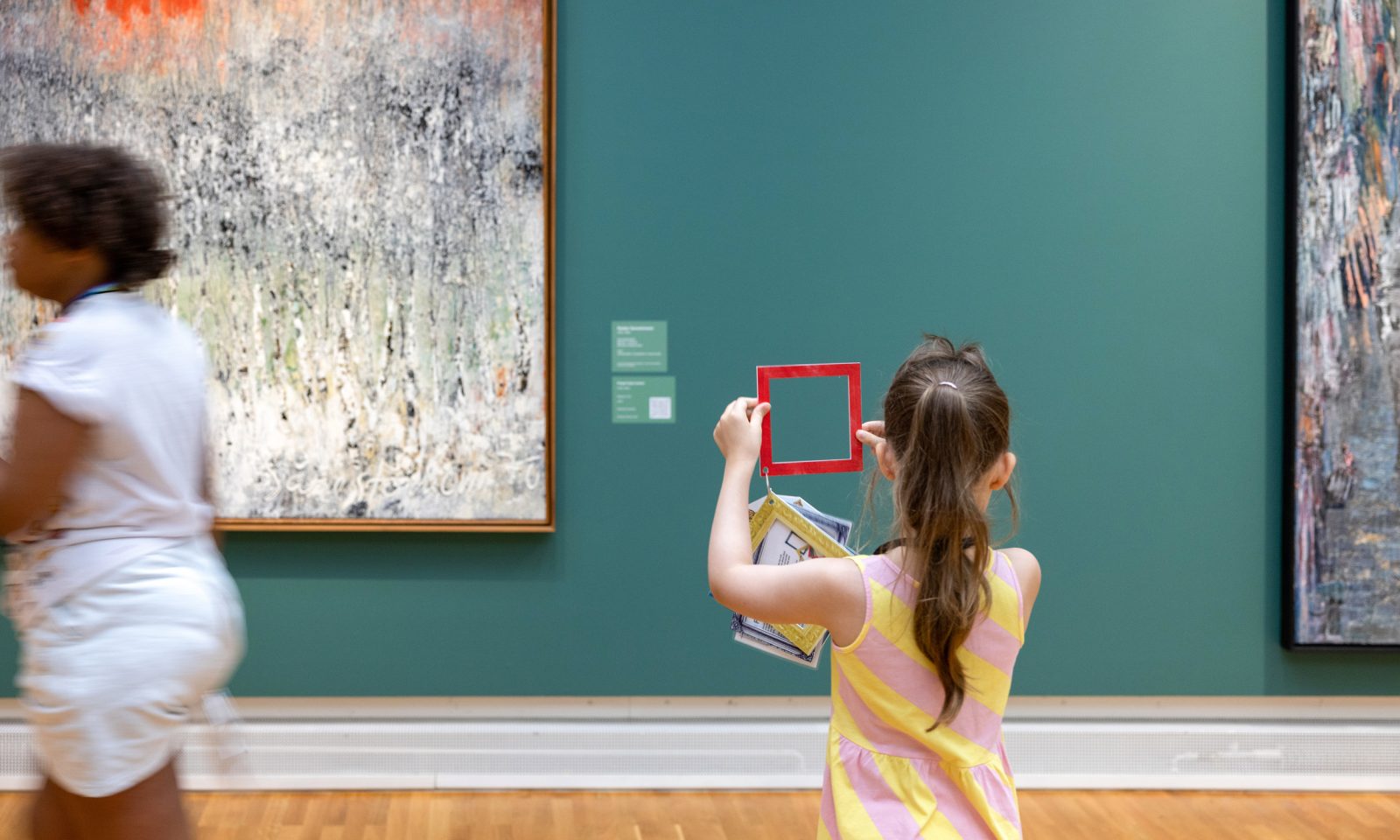 Tyttö tarkastelee isoa maalausta pienen pahvikehyksen läpi.